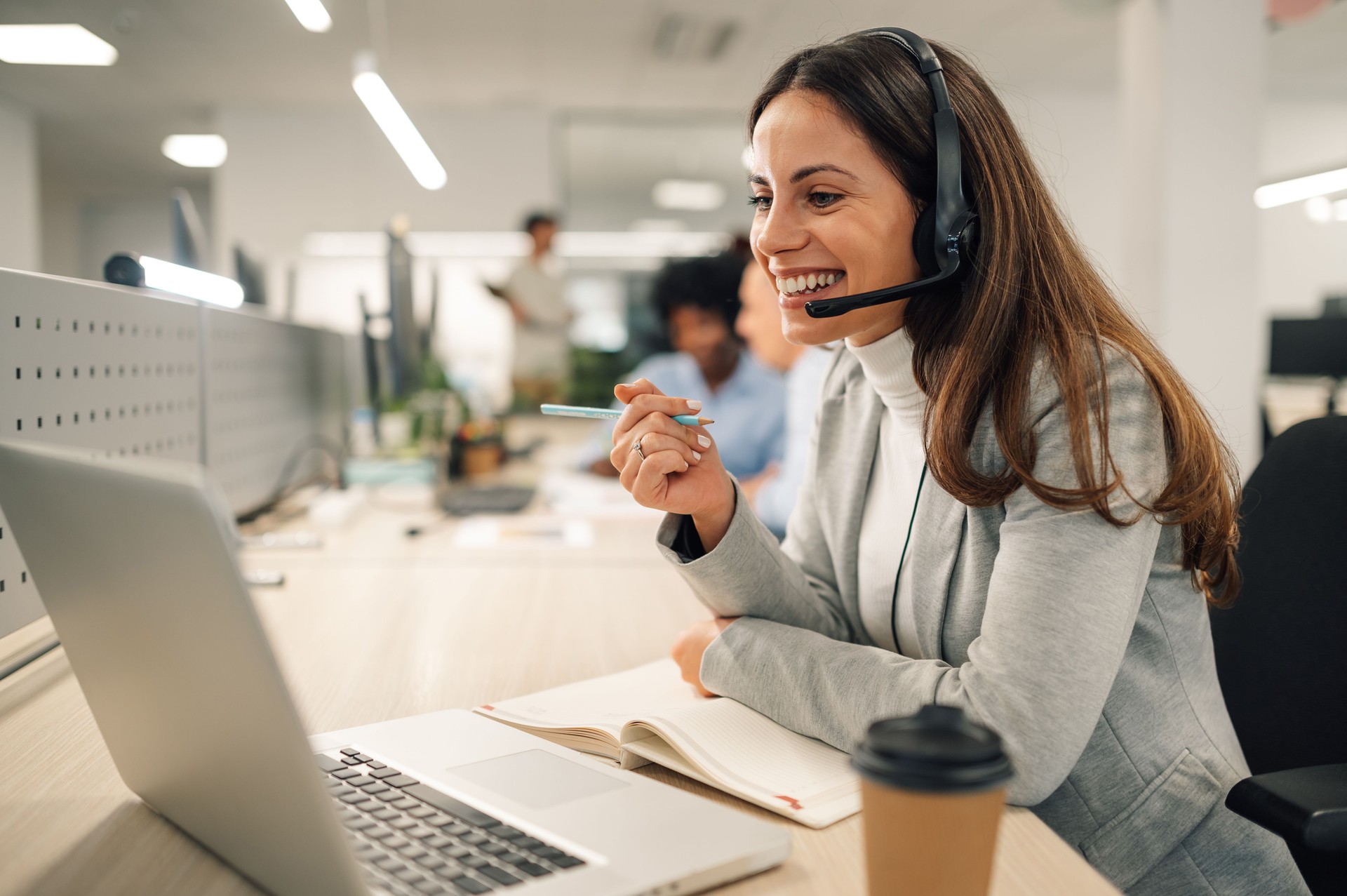 Kaukasische Geschäftsfrau mit Headset, die an einem Laptop in einem Callcenter arbeitet