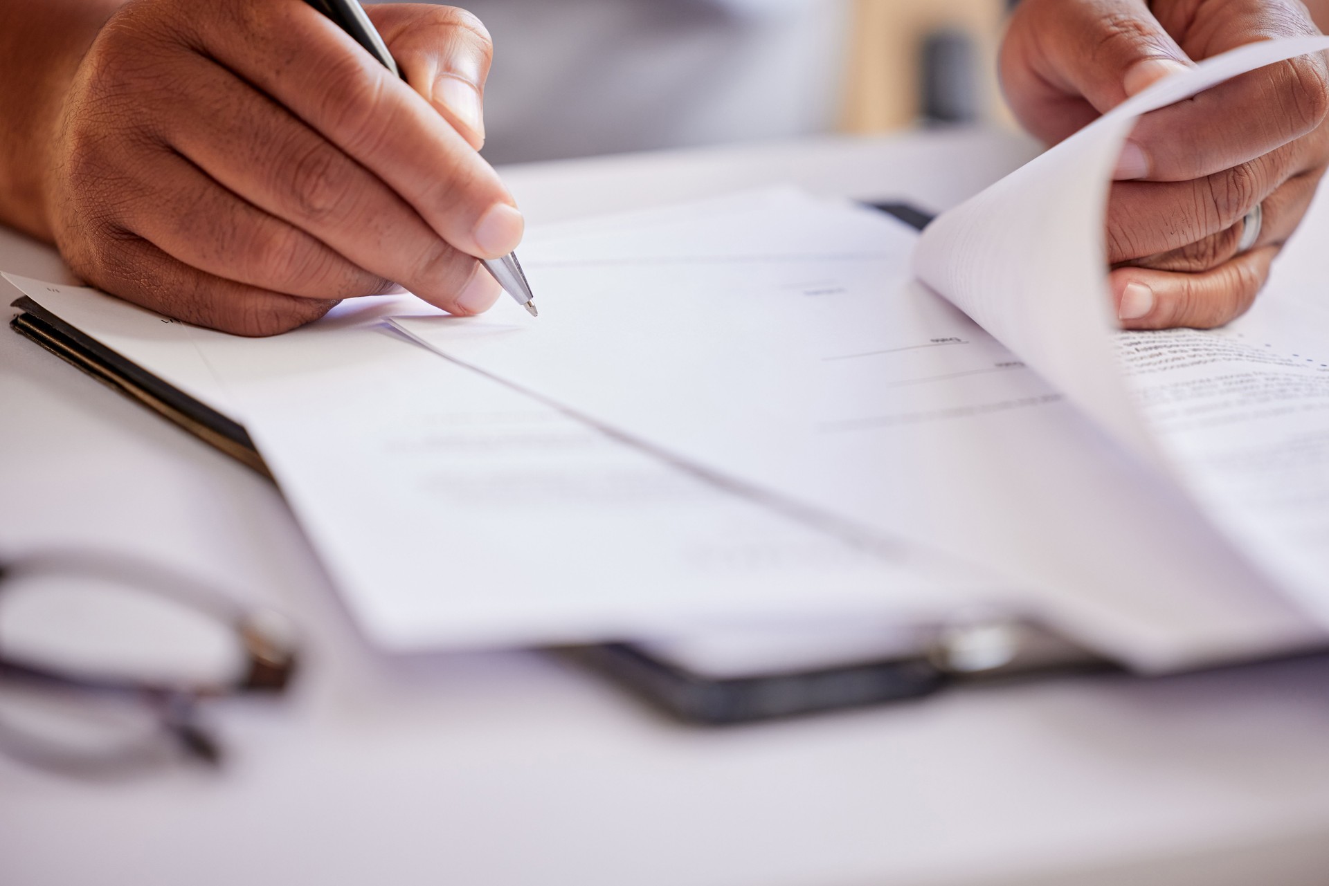 Abgeschnittene Aufnahme eines nicht wiederzuerkennenden Geschäftsmannes, der Papierkram ausfüllt, während er in seinem Büro sitzt